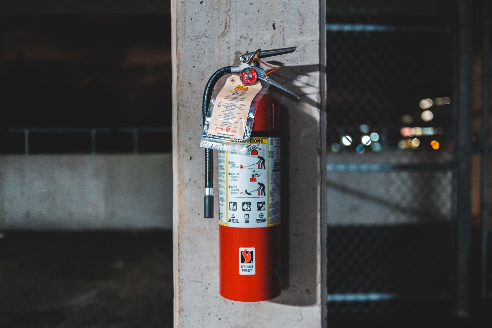 Red fire extinguisher mounted on a post with an inspection tag.