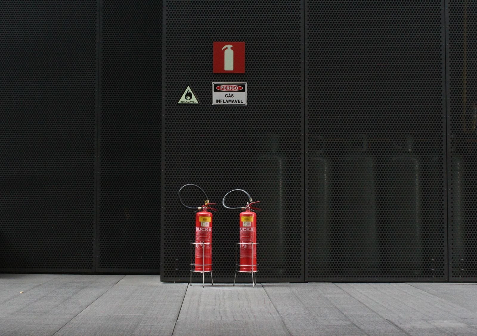 Two red fire extinguishers mounted side by side on a wall.