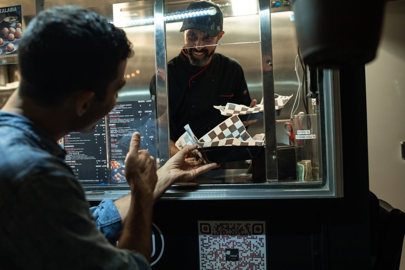Customer ordering at the service window of a food truck.